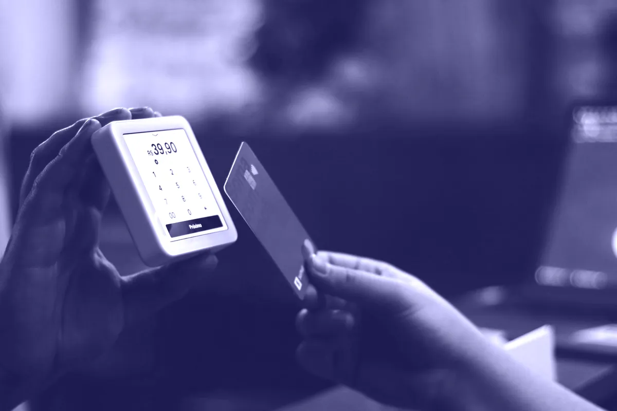 A hand tapping a card on a payment reader