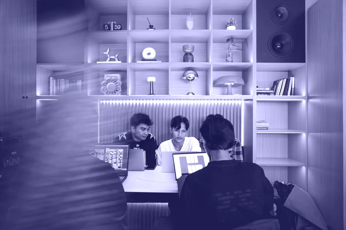 Three people at laptops in a warm wooden studio