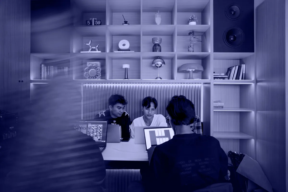 Three people at laptops in a warm wooden studio